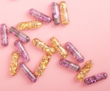 pile of sparkling drug capsules scattered on pink surface